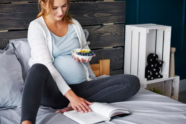 Femme enceinte prenant un repas en lisant