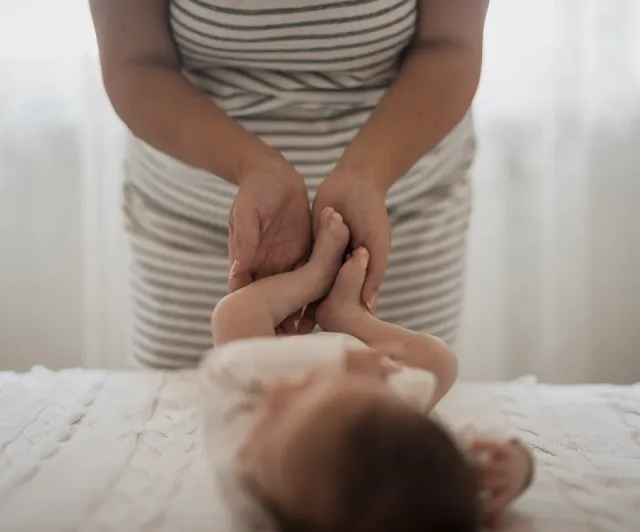 Mains d'une mère jouant avec les jambes de son bébé