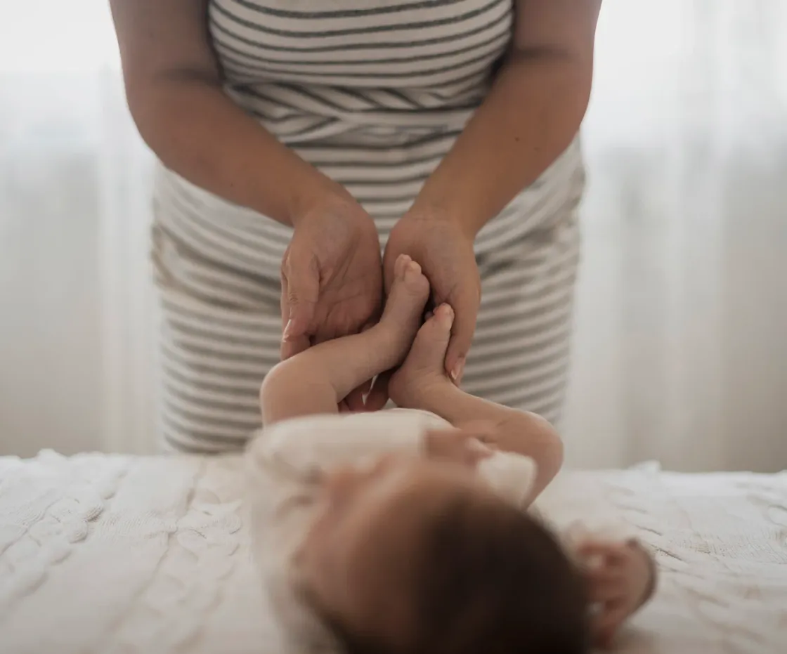 Mains d'une mère jouant avec les jambes de son bébé