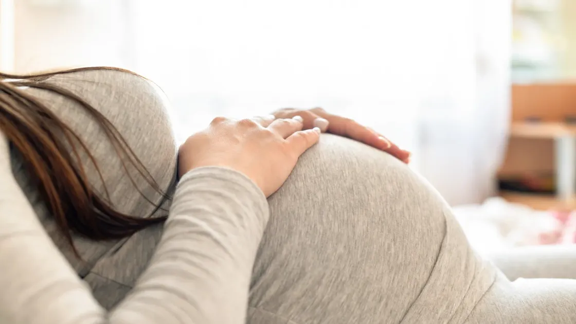 Femme enceinte allongée, les mains posées sur son ventre