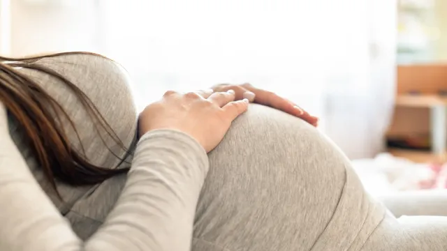 Femme enceinte allongée, les mains posées sur son ventre